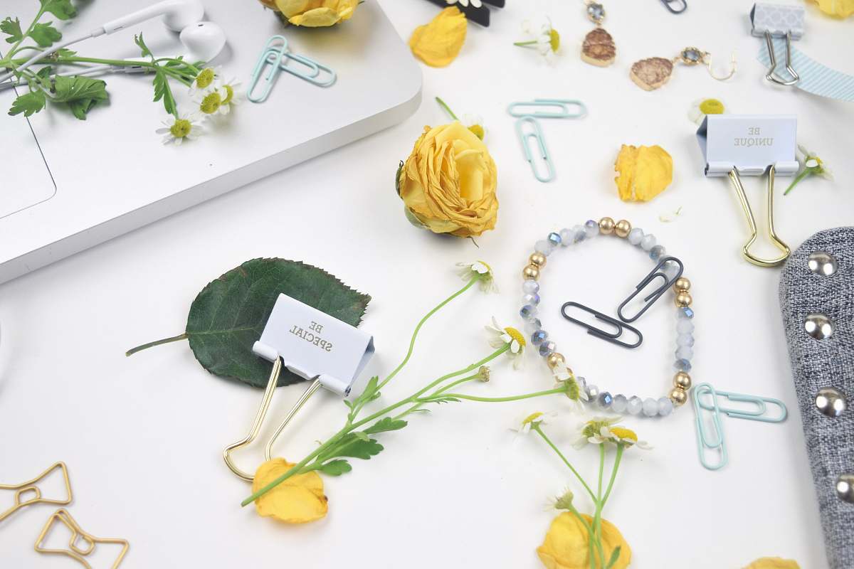 yellow florals flatlay photo of flowers, paper clips, and bracelet dragonfly ave